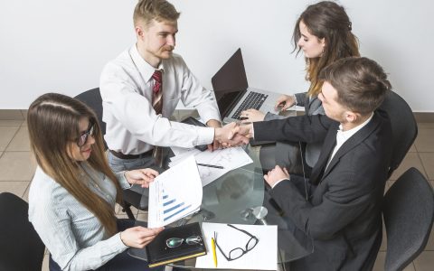 elevated-view-businessman-shaking-hands-with-his-partner-workplace